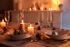 Image of holiday table set with dishes and candlelight.