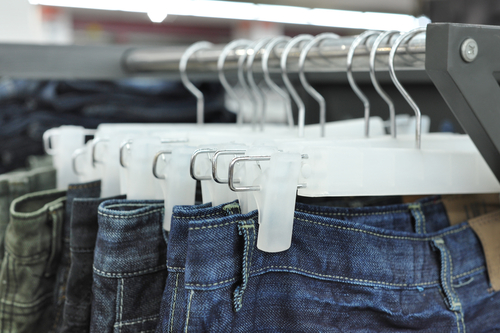Image of clothes rack with many pairs of jeans hanging on it.