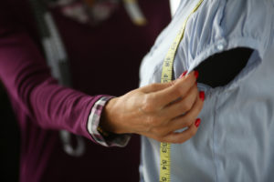Image of female arm measuring a shirt for alterations.